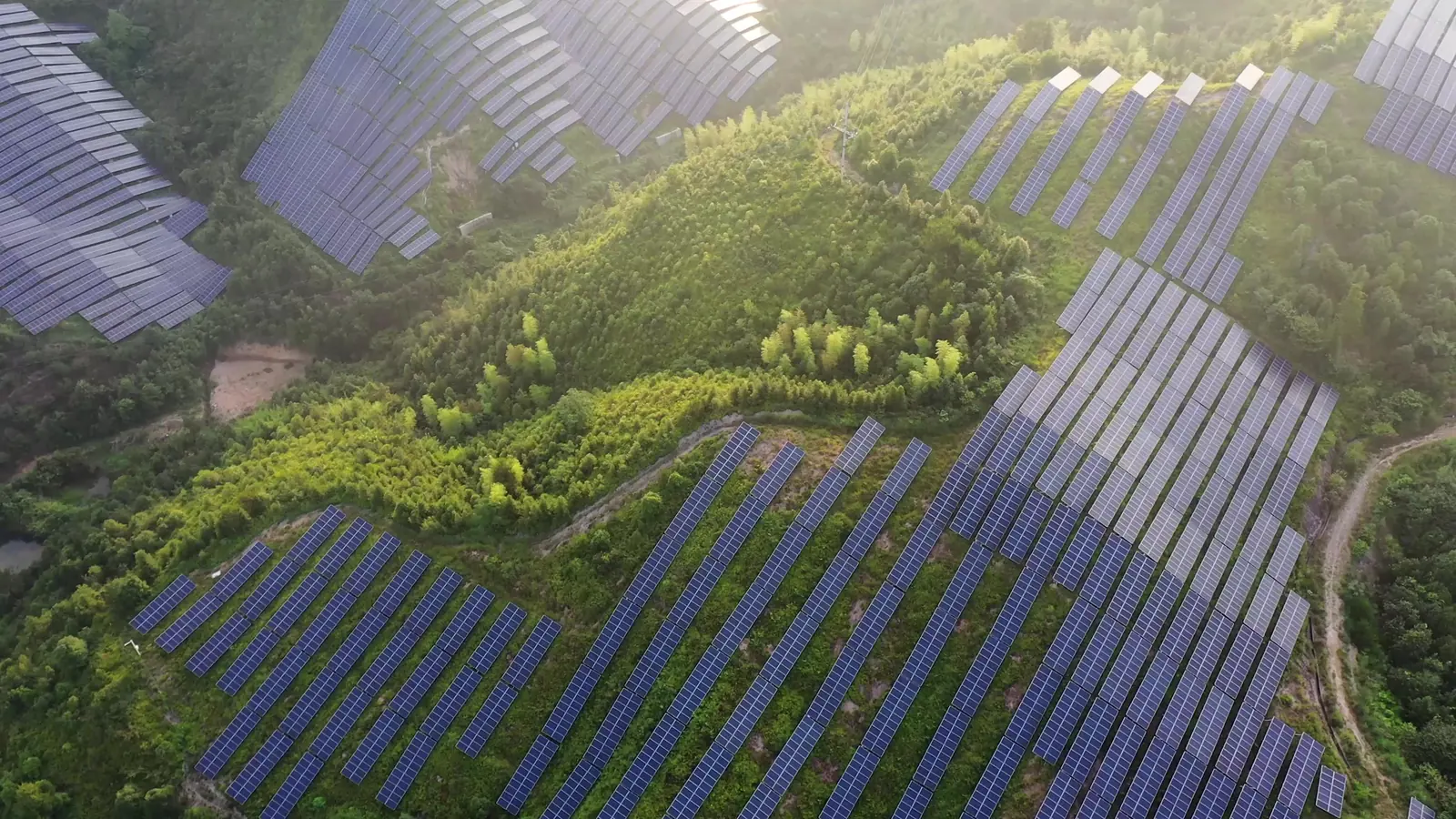 Luchtfoto van rijen zonnepanelen op een groene heuvel
